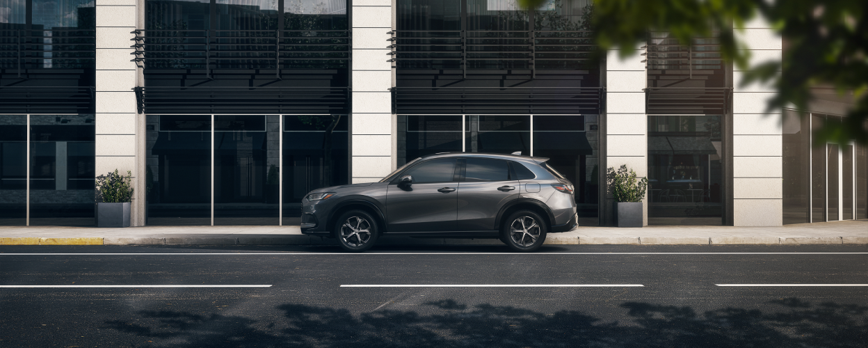 Sideview of grey HR-V parked outside a contemporary building in the city. 