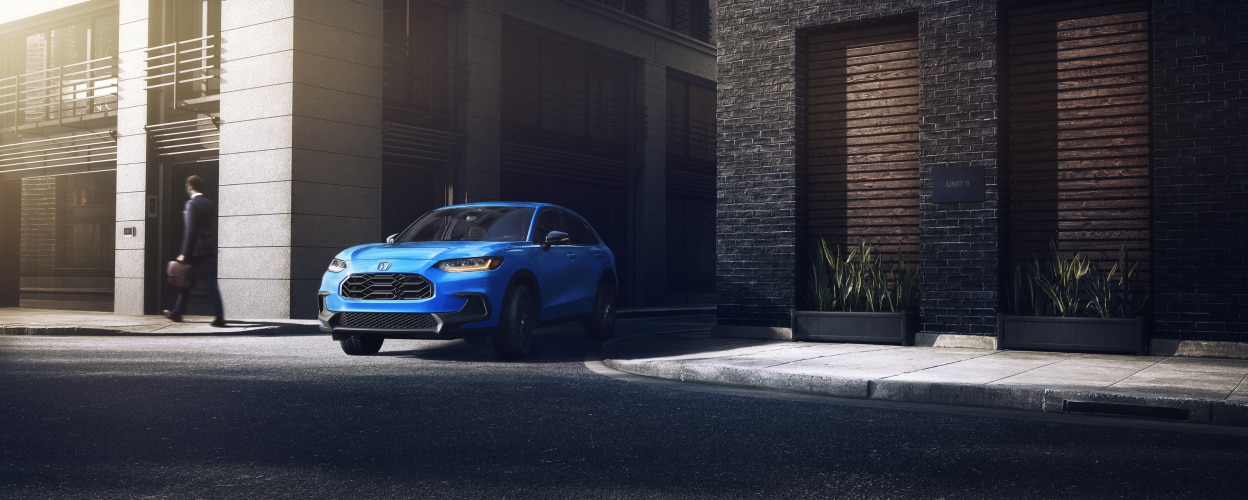 Vue 3/4 avant d’un HR-V bleu sortant d’une ruelle en ville.