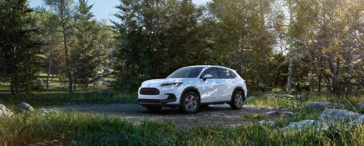Vue 3/4 avant latérale d’un HR-V blanc stationné dans la forêt.