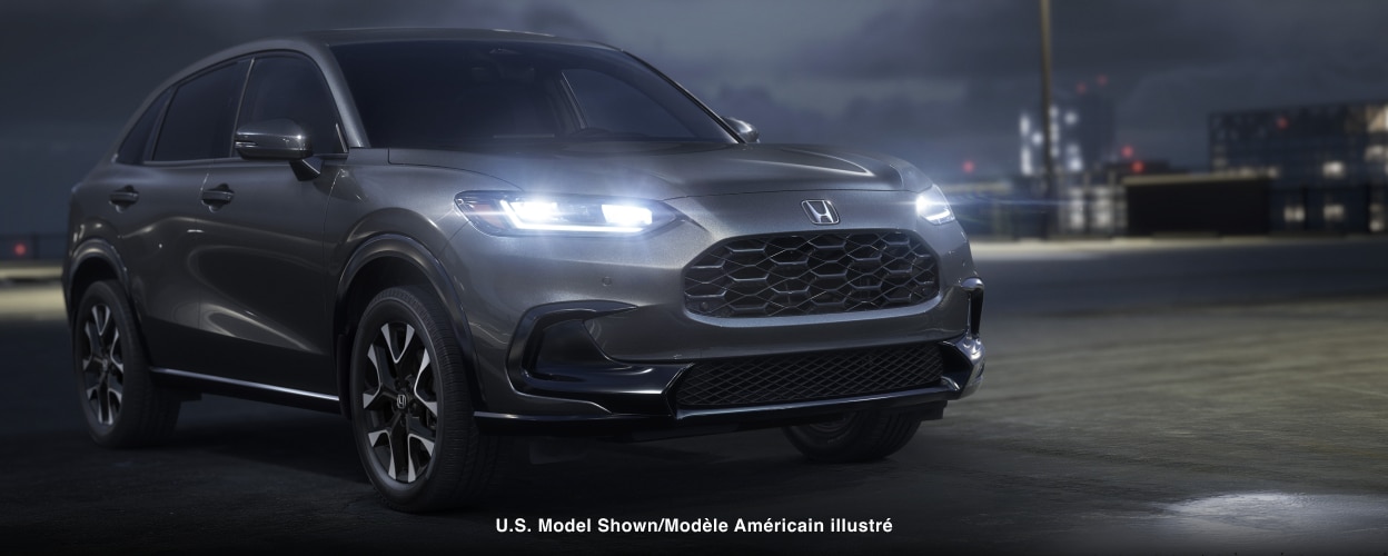 Vue 3/4 avant d’un HR-V gris stationné sur un toit, la nuit, avec phares à DEL allumés.