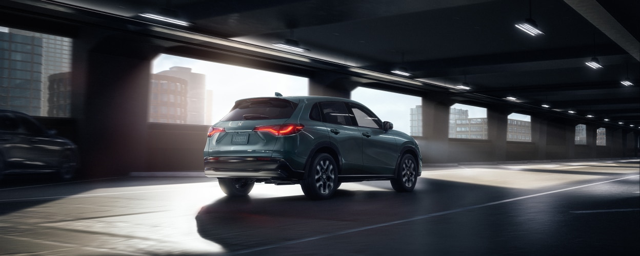 Vue 3/4 arrière d’un HR-V de couleur forêt nordique nacrée entrant dans un stationnement intérieur vide.