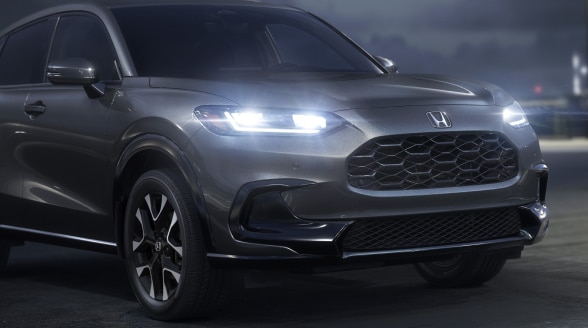 Vue 3/4 avant d’un HR-V gris stationné sur un toit, la nuit, avec phares à DEL allumés.