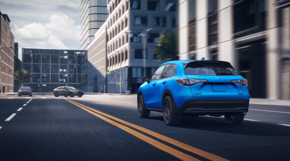 Vue 3/4 arrière d’un HR-V bleu circulant en ville.