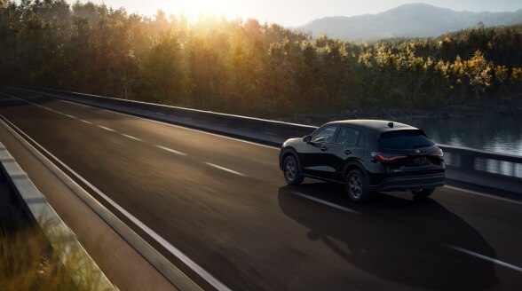 Vue 3/4 arrière d’un HR-V noir roulant sur un pont au-dessus d'un lac.