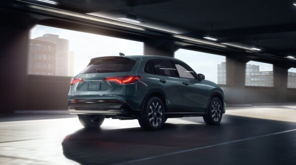 Vue 3/4 arrière d’un HR-V de couleur forêt nordique nacrée entrant dans un stationnement intérieur vide.