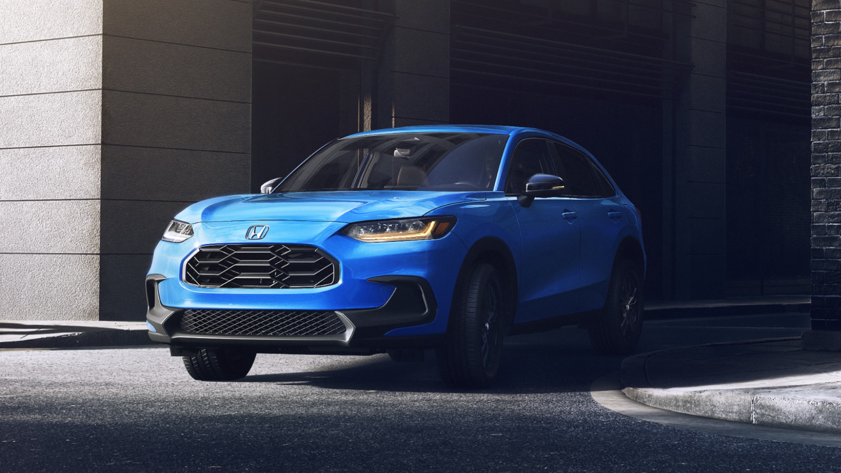 Vue 3/4 avant d’un HR-V bleu sortant d’une ruelle en ville.