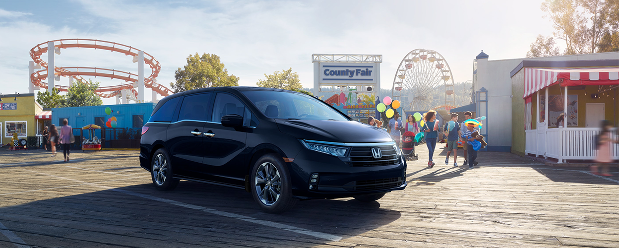 3/4 front view of black Honda Odyssey parked outside a county fair.