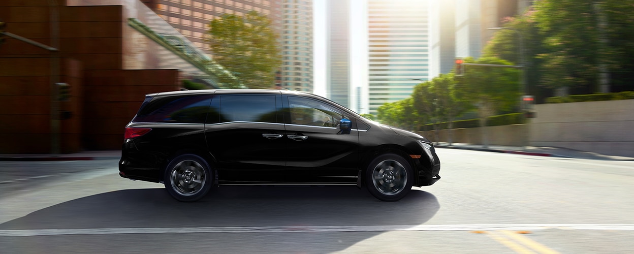 Sideview of black Honda Odyssey driving on city street.