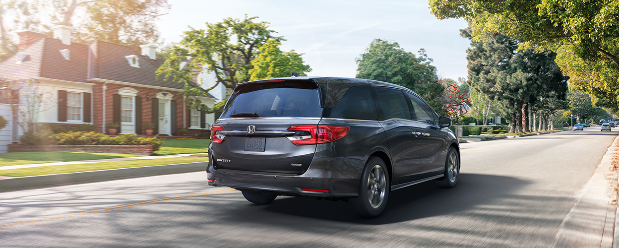 3/4 rear view of black Odyssey driving in suburban street.