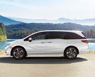 Sideview of white Odyssey, parked lakeside.