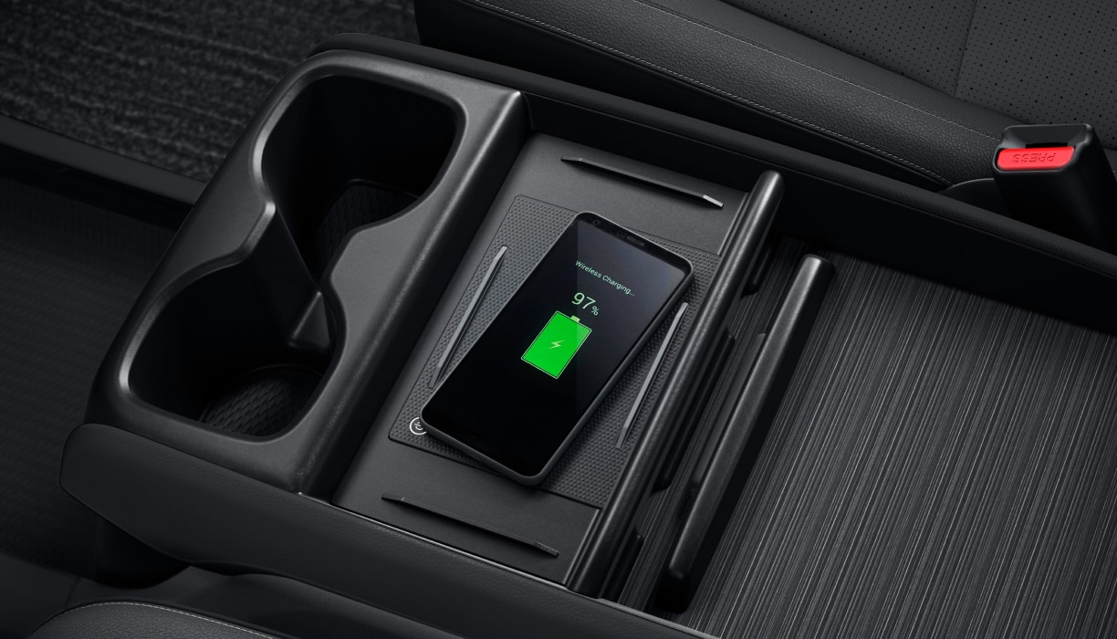 Plan en plongée d’un téléphone en cours de recharge sur la console centrale.