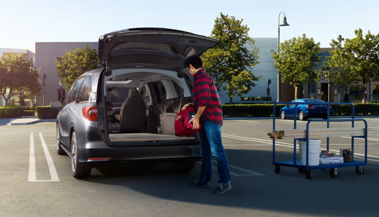 Un homme charge l’espace de chargement d’une Odyssey dans un stationnement vide.