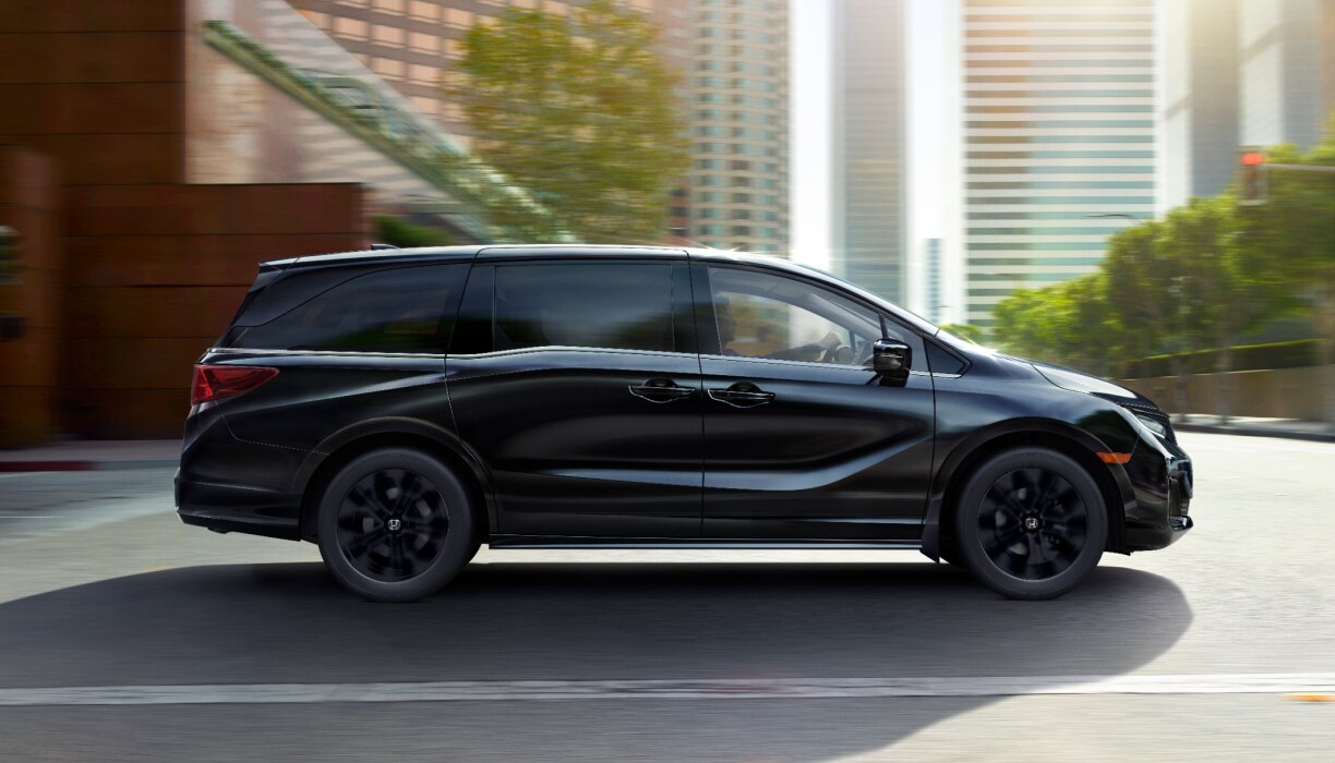 Vue latérale d’une Odyssey noire circulant en ville.