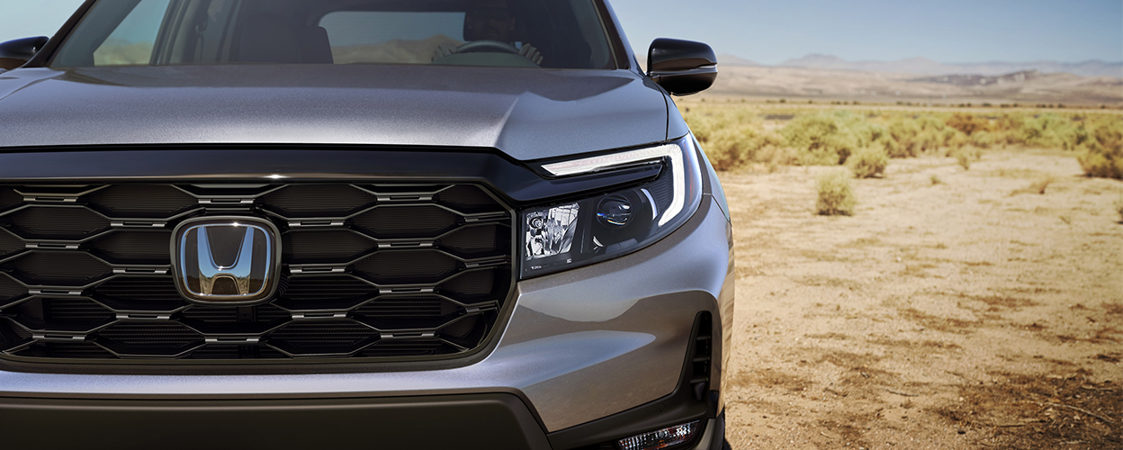 Closeup of grill on grey Honda Passport in desert.