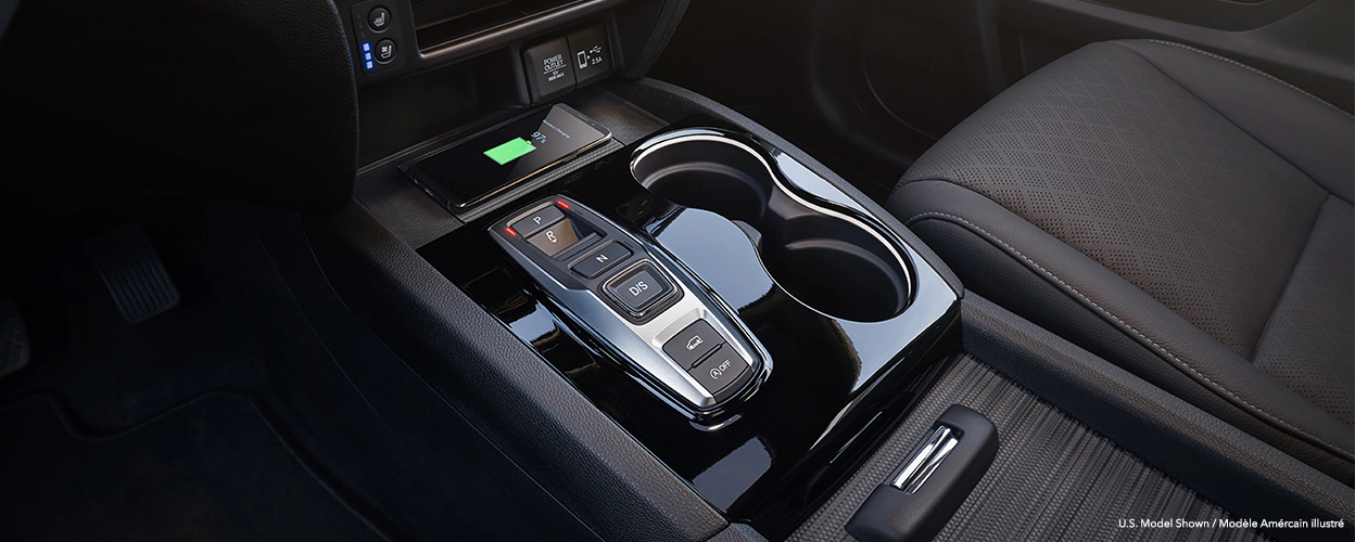 Closeup of centre console and phone charging on pad.