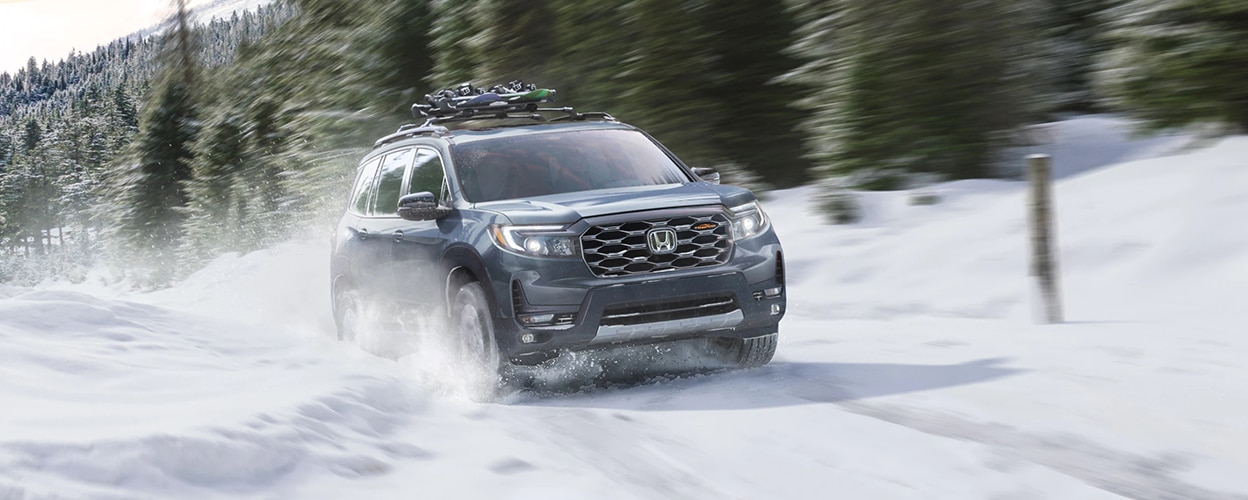 3/4 front view of Honda Passport driving snowy forest road.