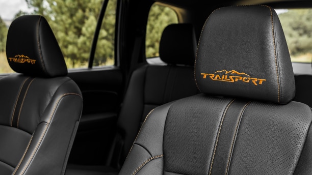 Closeup of Passport’s front seats with orange contrast stitching and “TrailSport” logo on headrests.