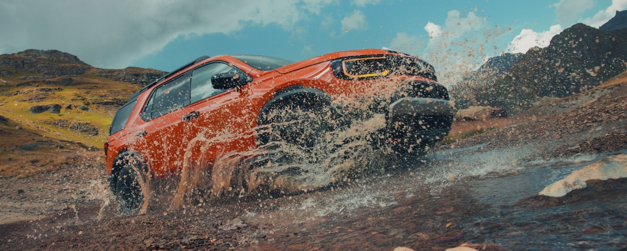 An orange Passport splashes through a puddle.