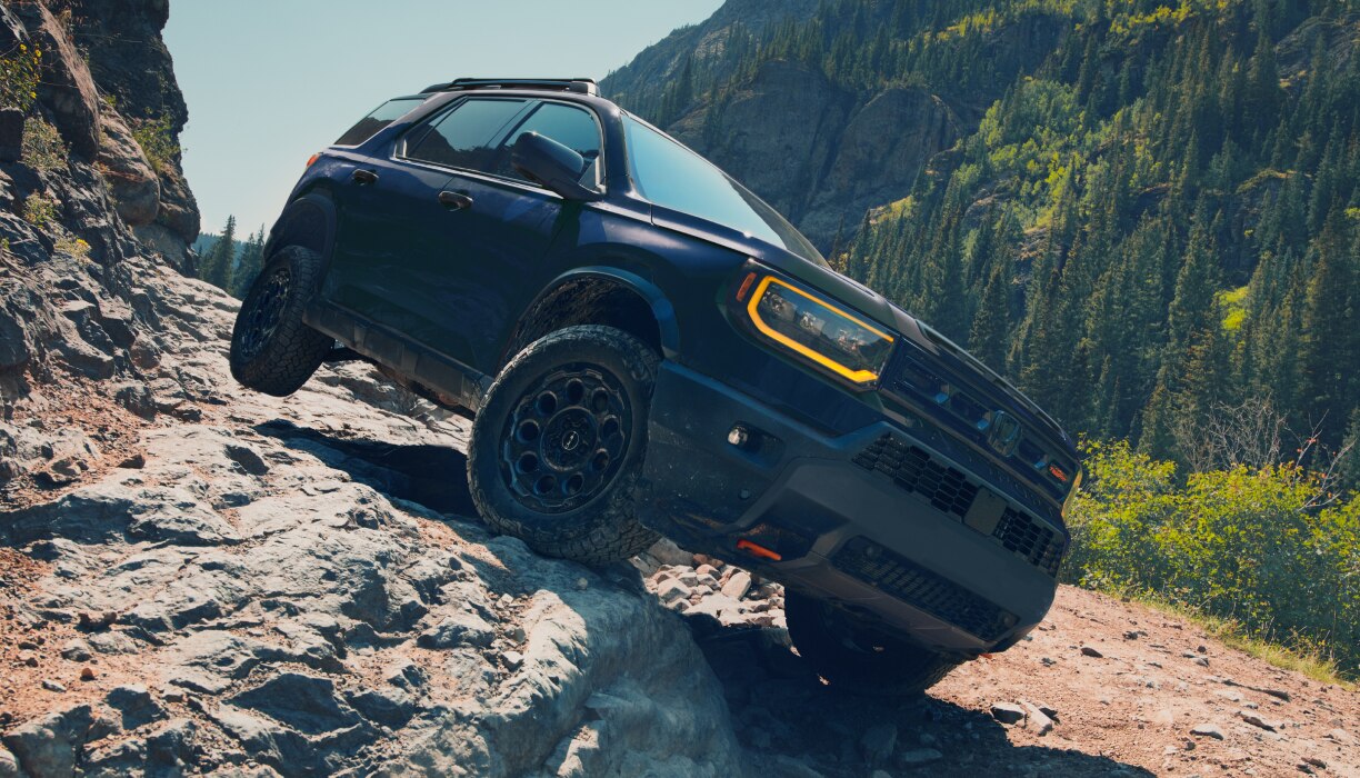 A blue Passport drives over rough mountain terrain. 