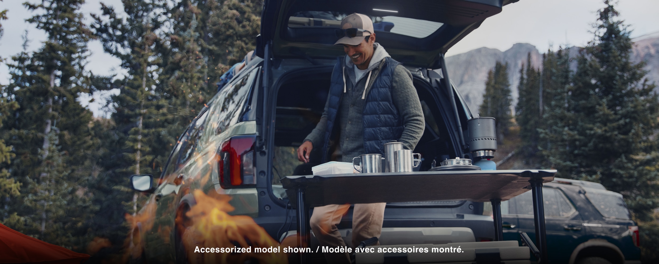 Un homme organise une zone pour cuisiner, en camping, derrière un Passport.