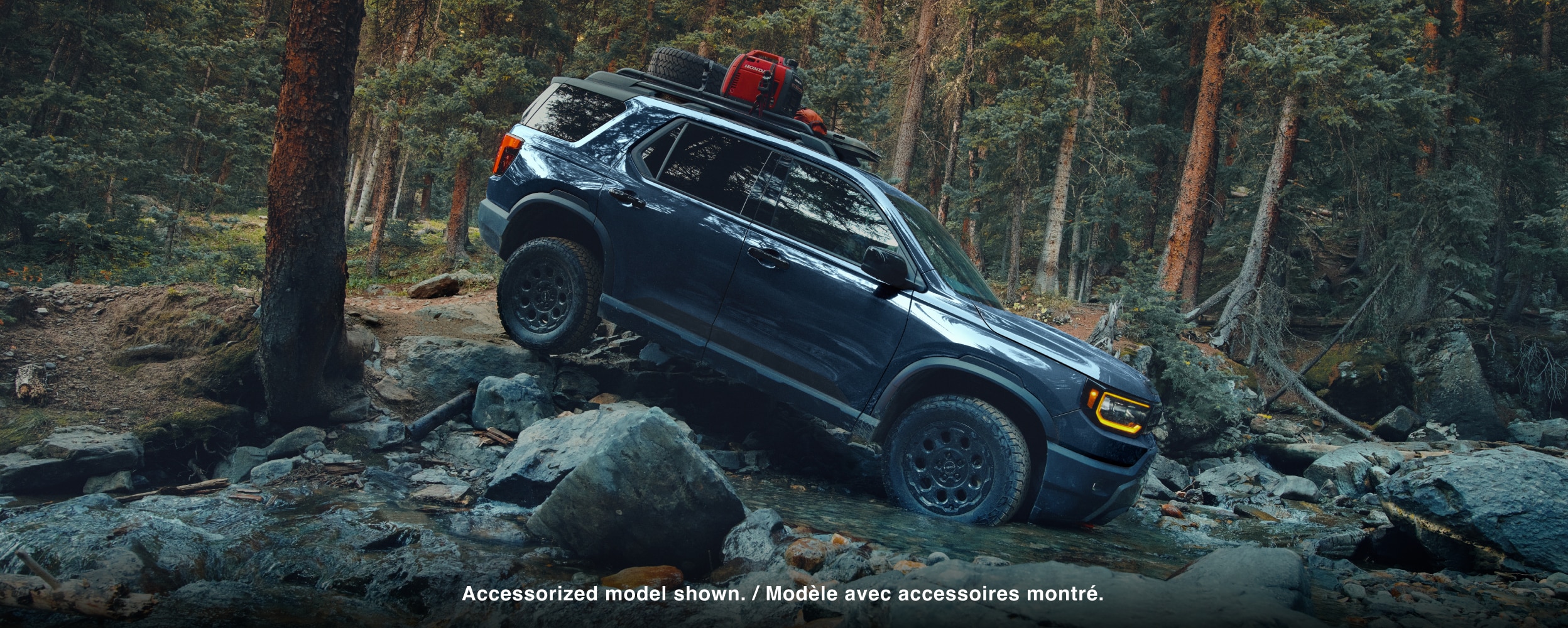 A blue Passport drives over rough mountain terrain.