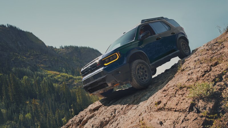 A blue Passport drives over rough mountain terrain. 