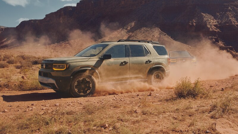 A green Passport drives through dusty desert terrain. 
