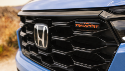 Closeup of front of light blue Pilot, showcasing its grille and the “TrailSport” emblem. 