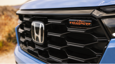 Closeup of front of light blue 2023 Pilot, showcasing its grille and the “TrailSport” emblem.
