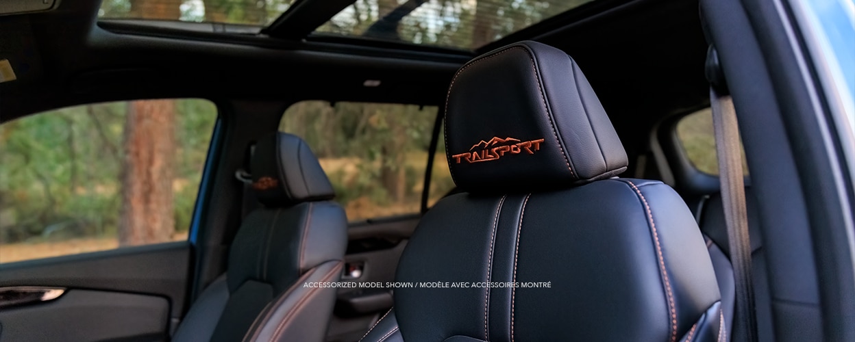 View of front seats on Honda Pilot TrailSport, showcasing the front seat’s orange stitching and “TrailSport” logo on headrests and the new one-touch power panoramic moonroof.