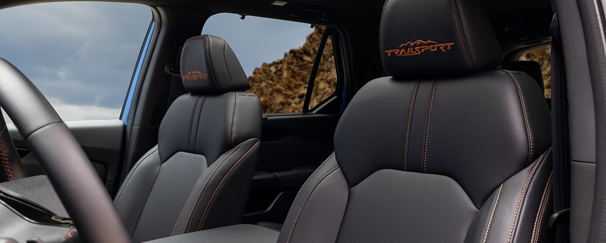 View of front seats on Pilot TrailSport, showcasing the front seat’s orange stitching and “TrailSport” logo on headrests and the new one-touch power panoramic moonroof.