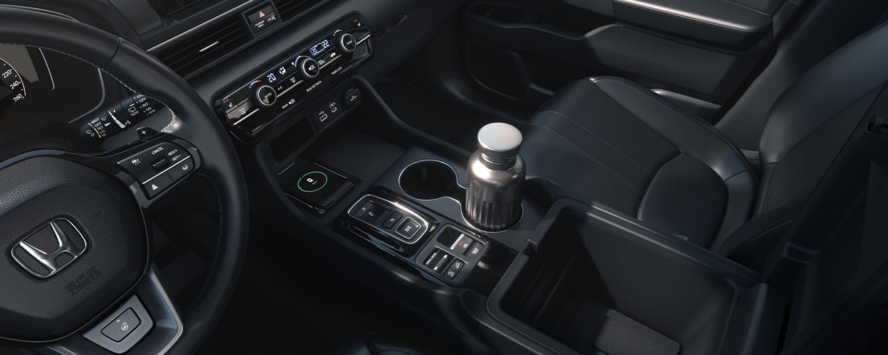 Plan de trois quarts intérieur en plongée montrant la rangée avant et la console centrale, avec une bouteille d’eau dans le porte-gobelet.