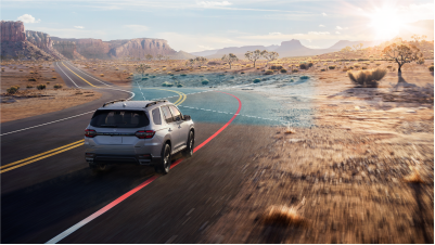 Plan de trois quarts arrière d’un Pilot gris négociant une courbe sur une autoroute désertique. Des ondes et des lignes bleues jaillissent depuis l’avant et détectent les marques blanches sur la chaussée.