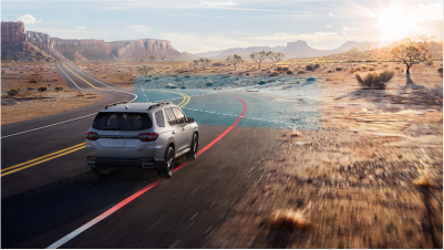Plan de trois quarts arrière d’un Pilot gris négociant une courbe sur une autoroute désertique. Des ondes et des lignes bleues jaillissent depuis l’avant et détectent les marques sur la chaussée. 