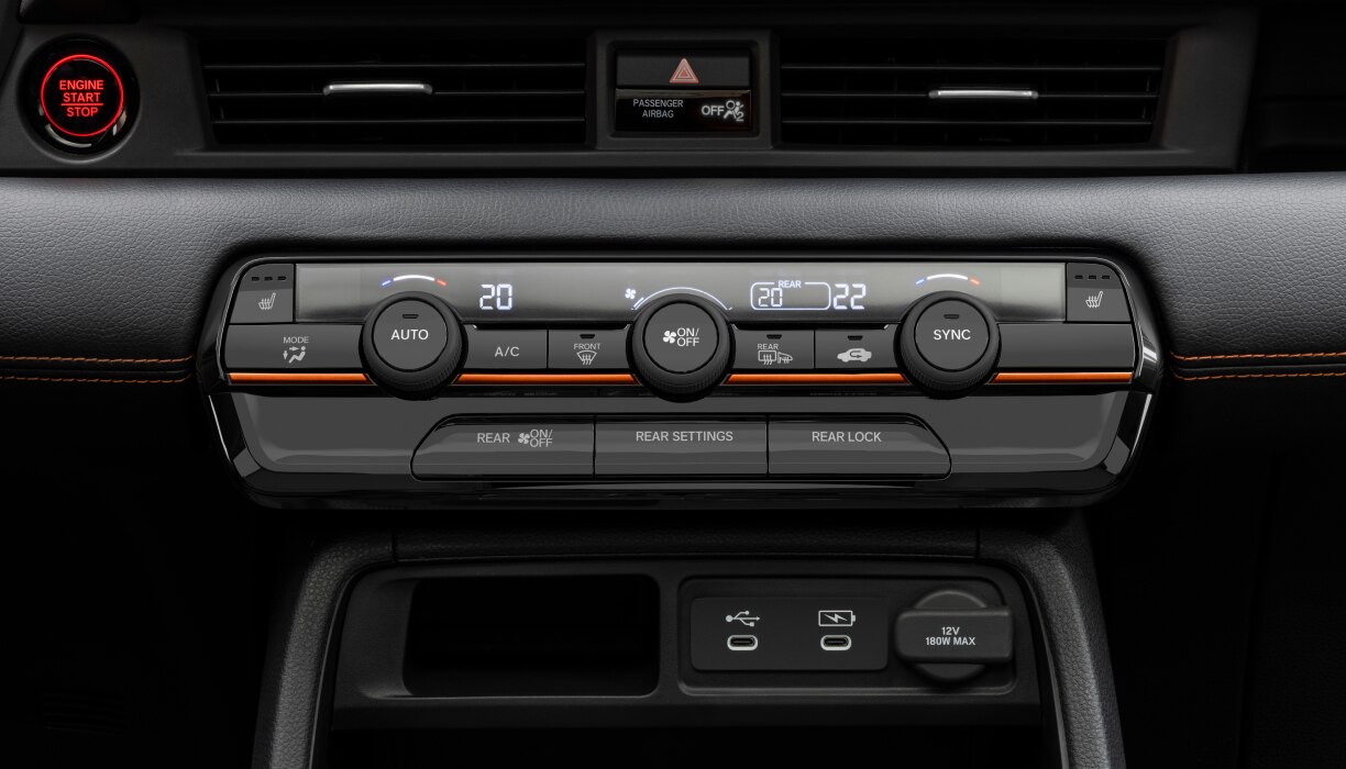 Gros plan sur le panneau de commande de la climatisation du Pilot, avec les boutons et les cadrans de réglage de la température.