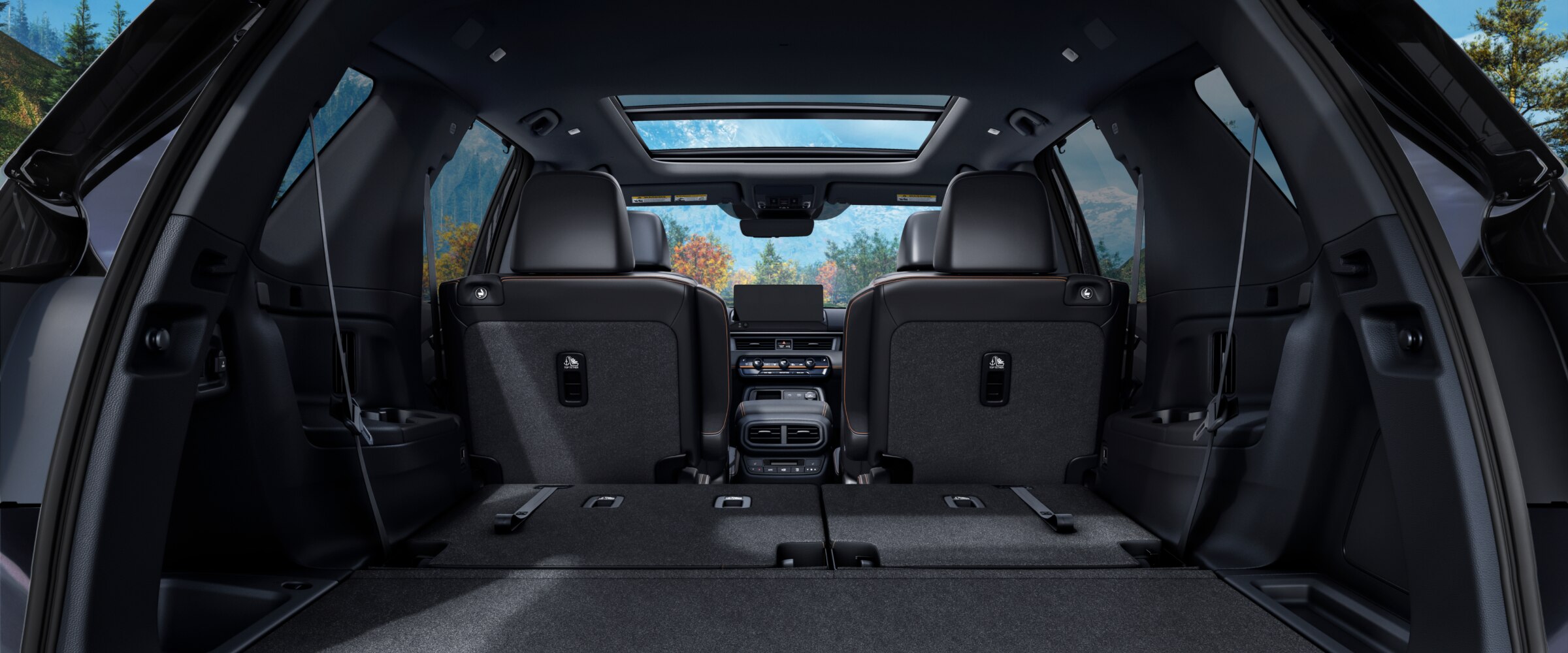 Vue arrière de l’habitacle du Pilot depuis le coffre ouvert, avec la rangée de sièges arrière rabattue pour mettre en valeur l’espace de chargement.