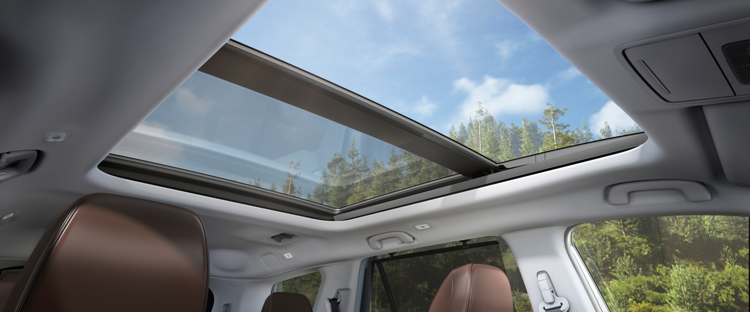 View from the Pilot's interior, looking upwards at blue skies and trees through the panoramic moonroof.
