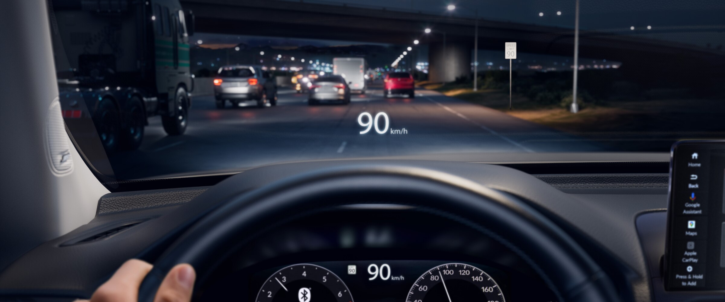 Vue de l’intérieur depuis le siège du conducteur, montrant le tableau de bord et le volant, avec des jauges visibles à l’arrière. Une main repose sur le volant et la vitesse du véhicule est affichée sur le pare-brise.