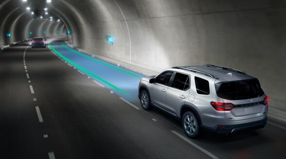 Vue de trois quarts arrière d’un Pilot argenté traversant un tunnel avec des capteurs bleus et verts surveillant la voie devant lui.