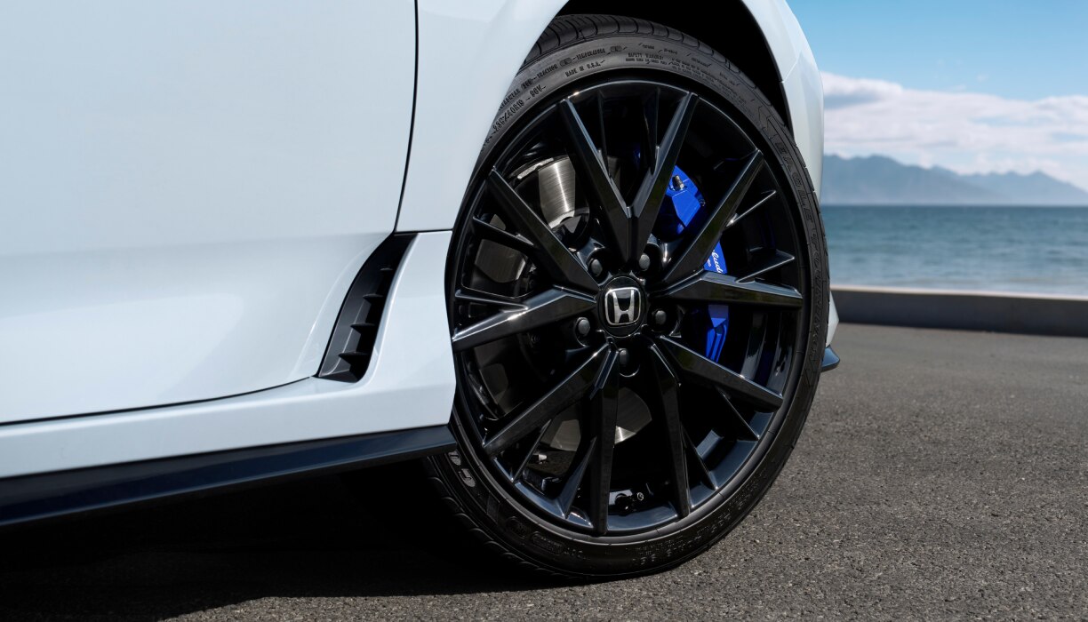 Closeup of the black front wheel on a white Prelude.