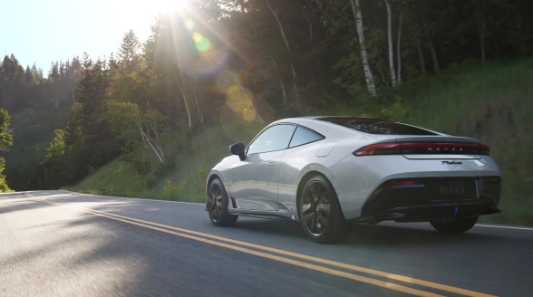 Vue de trois quarts arrière d’une Prelude argent roulant sur une route bordée d’arbres.