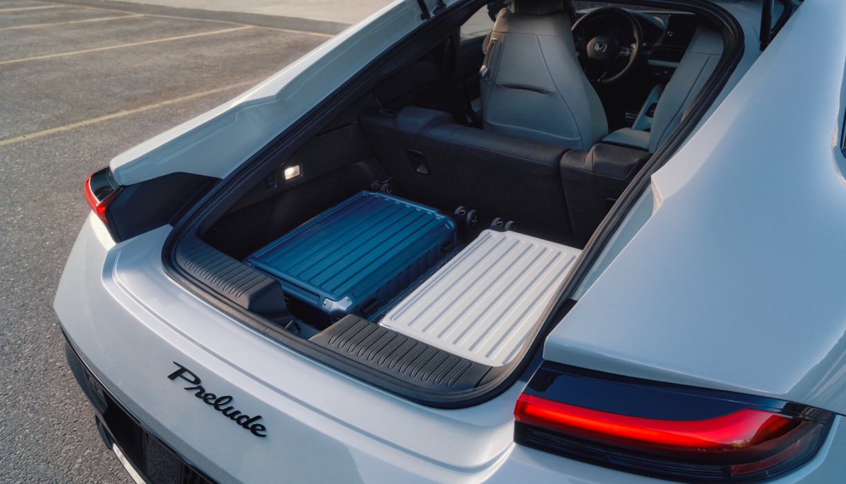Vue arrière du coffre ouvert d’une Prelude blanche avec deux valises en plastique à l’intérieur.