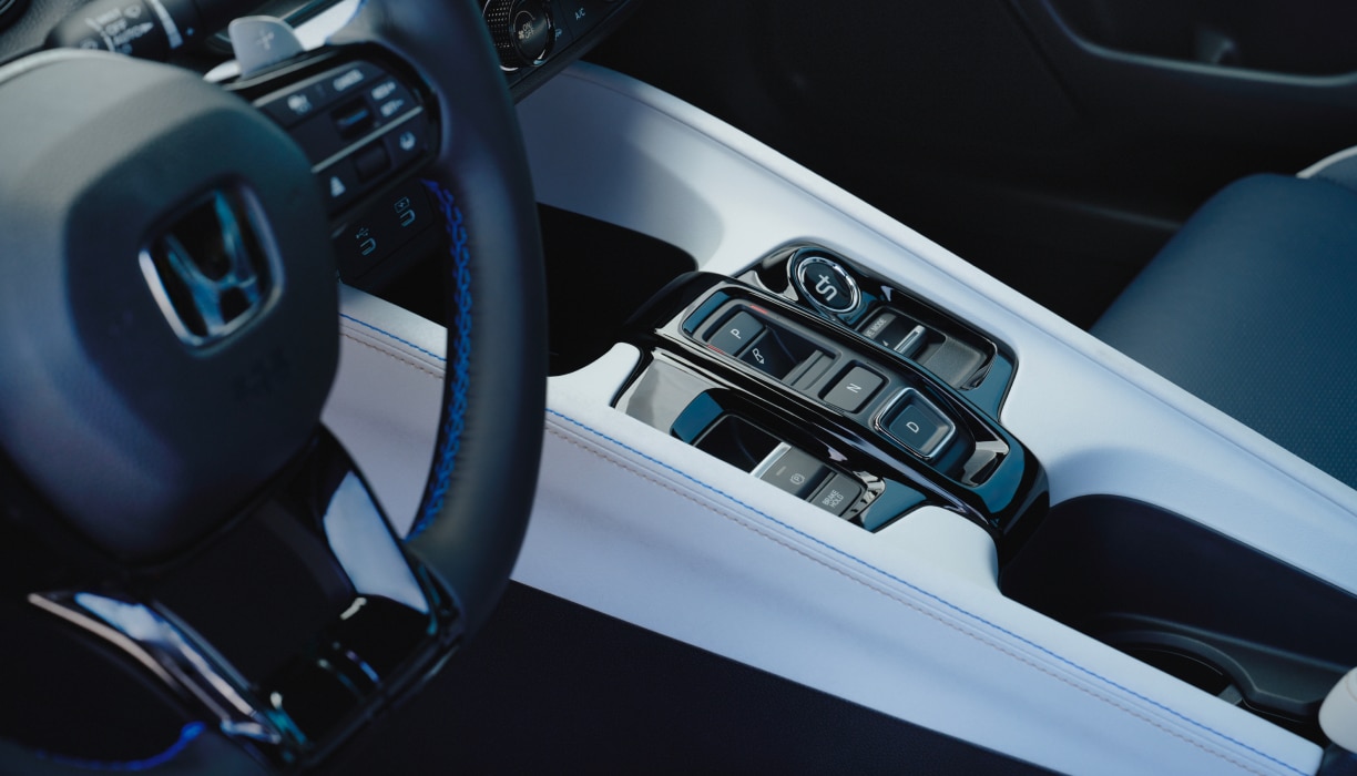 Closeup of Prelude's centre console, showcasing the button controls, cupholders and wireless charging pad. 