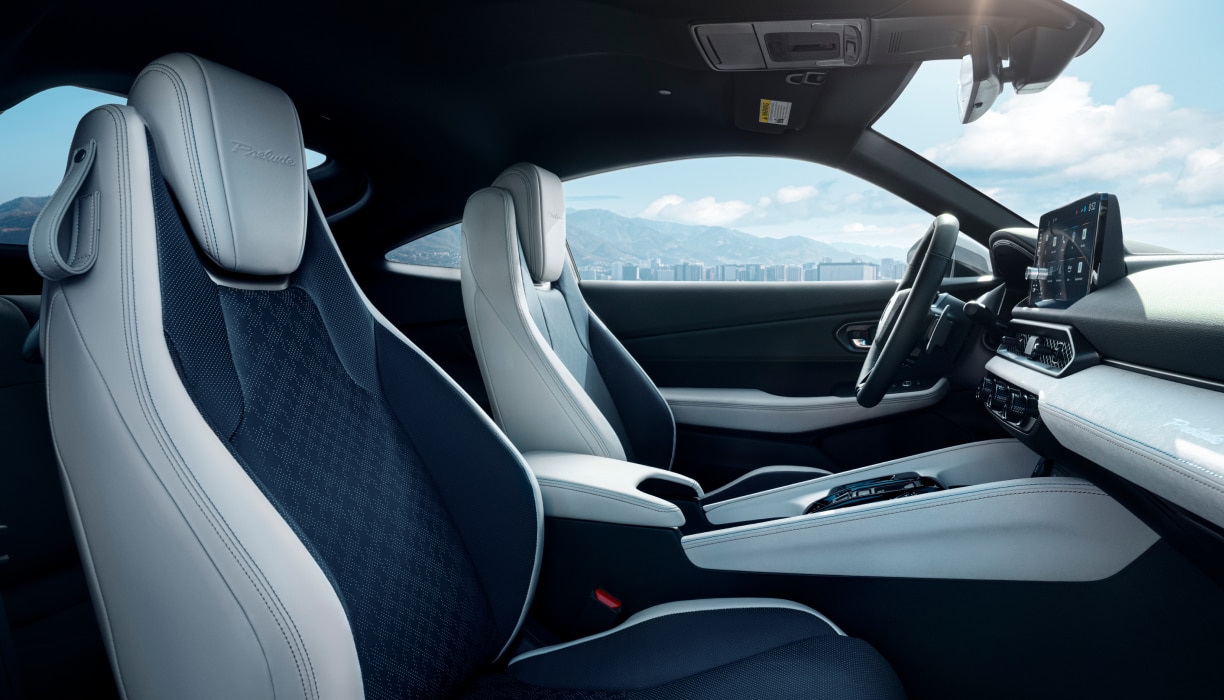 Passenger's side view of black and white front row seating, steering wheel, and dashboard.