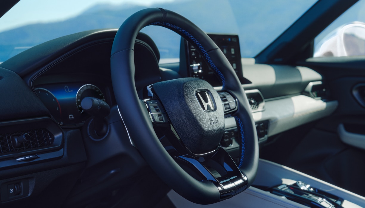 Side view of steering wheel. Centre console, dashboard, and touchscreen can be seen in the background.