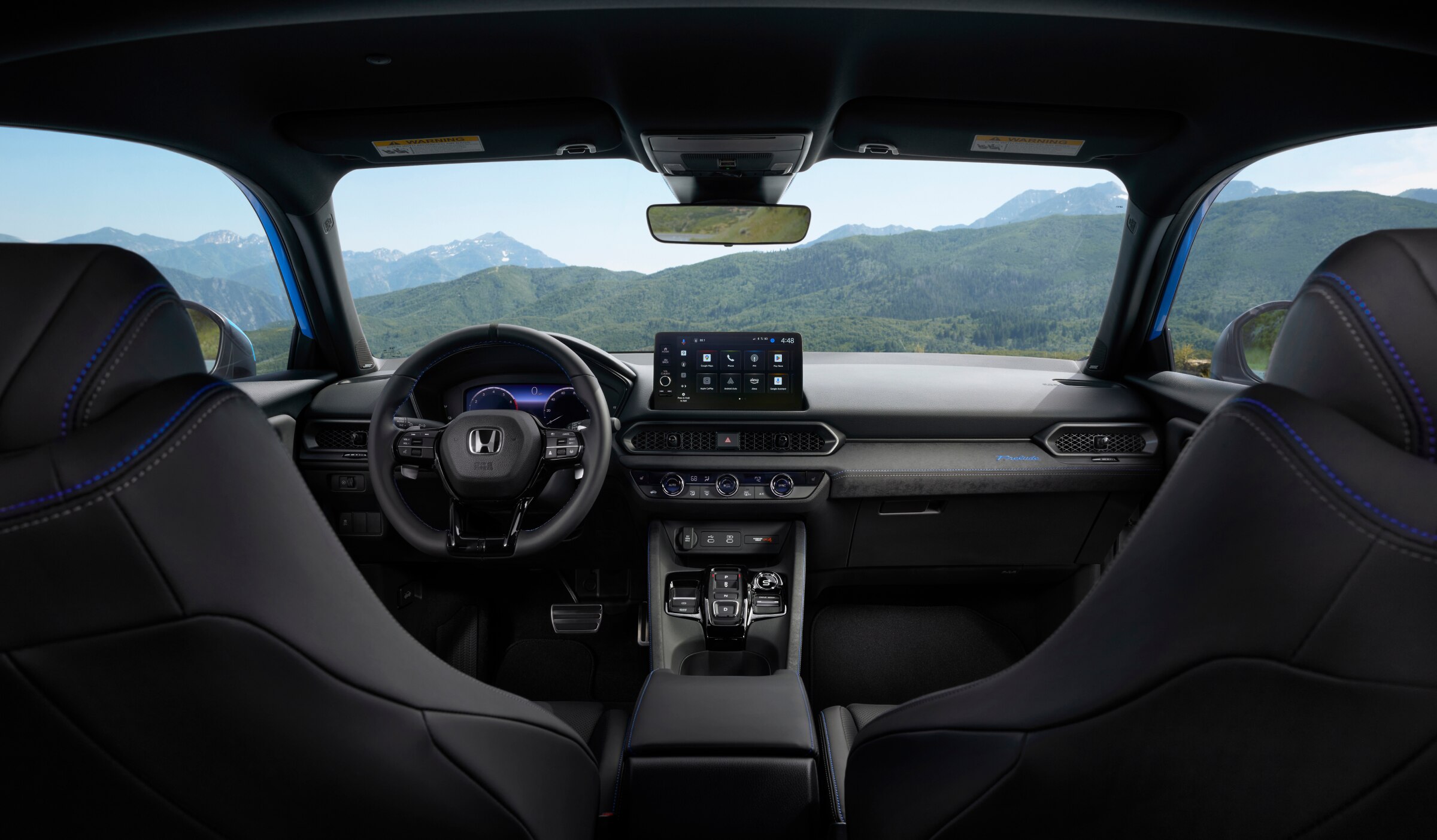 Interior image of Prelude's cockpit, as seen from the backseat. Out the windshield and windows is a mountain landscape. 