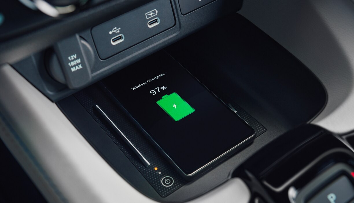 Closeup view of a compatible smartphone charging wirelessly on the charging pad in Prelude's centre console. 