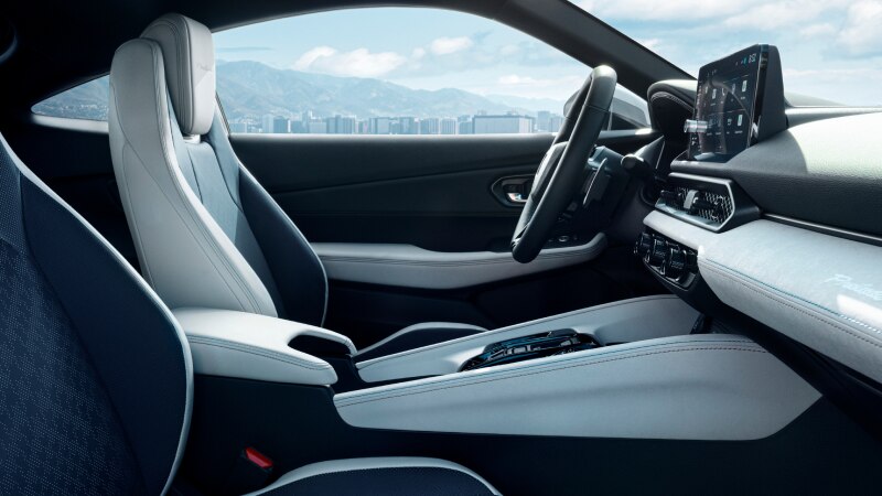 Medium closeup of side view of driver's seat, with centre console and dashboard in the foreground. 