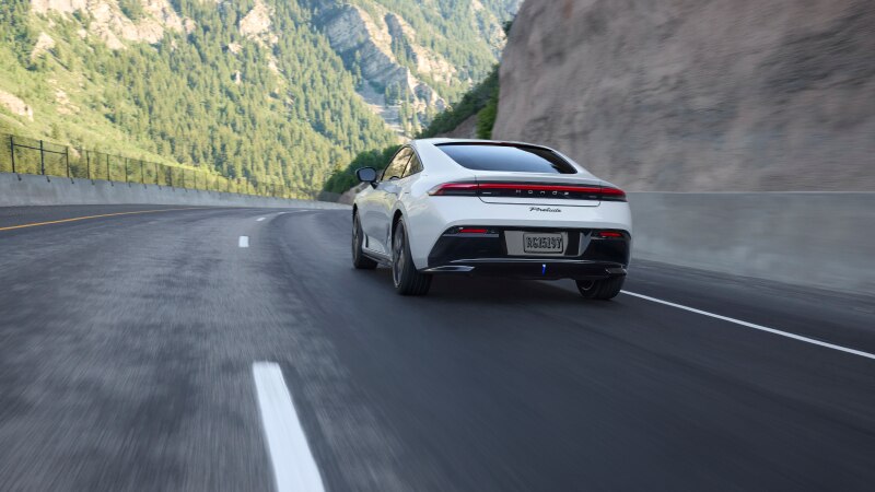Rear view of a white Prelude driving on a mountain highway. 