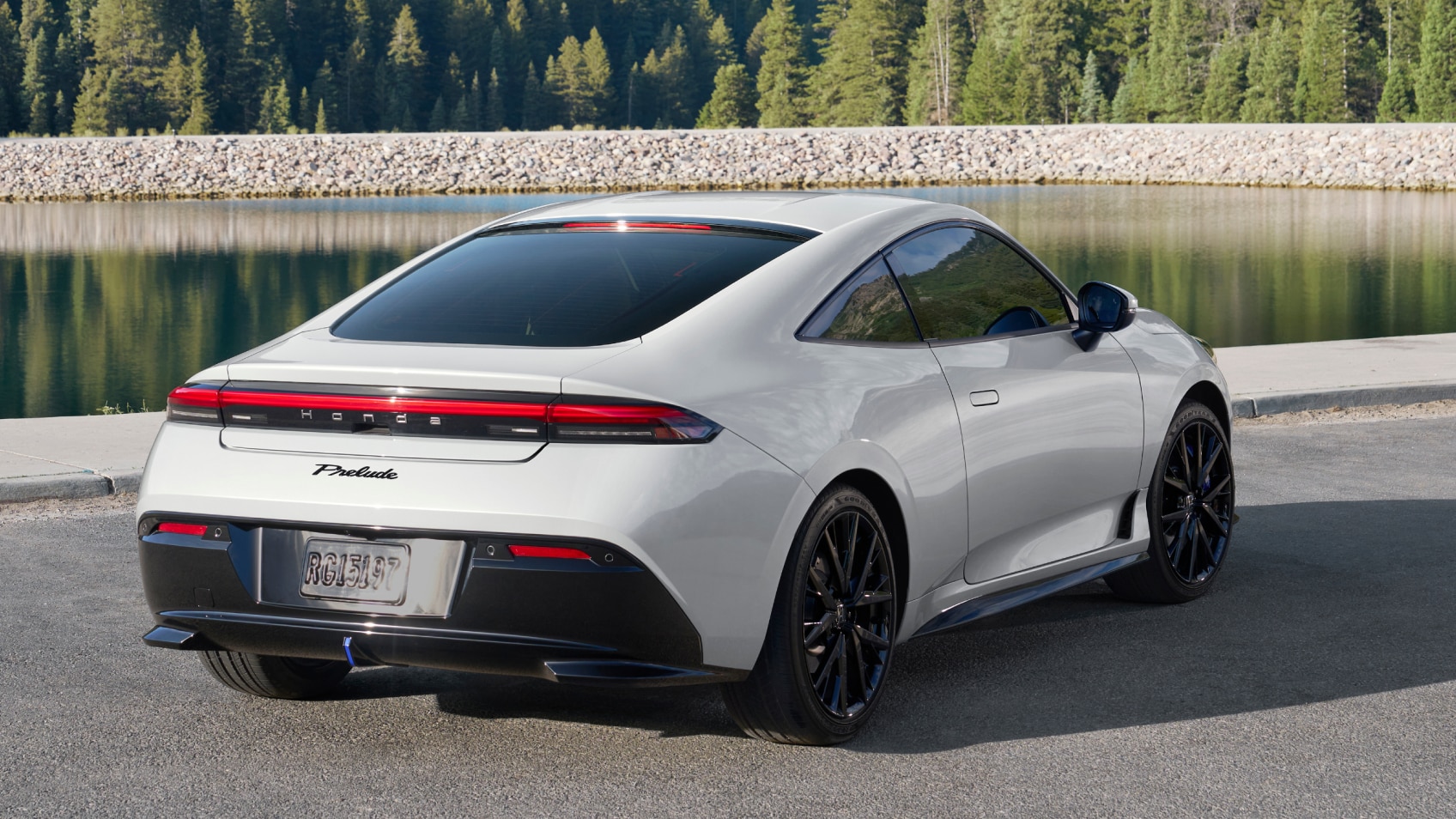 Rear view of white Prelude parked against a backdrop of forest, rocks, and water.